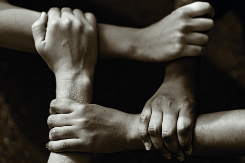 Multiracial people with black, latin, caucasian and asian hands holding each other wrist. Unit and concord in multiethnic team. Tolerance, teamwork and anti racism concept. Image